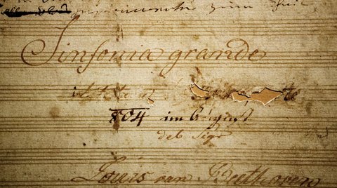 Nahaufnahme einer alten Partitur mit der Aufschrift "Sinfonia grande". Zart geschriebene Notizen und verblasste Linien sind sichtbar.
